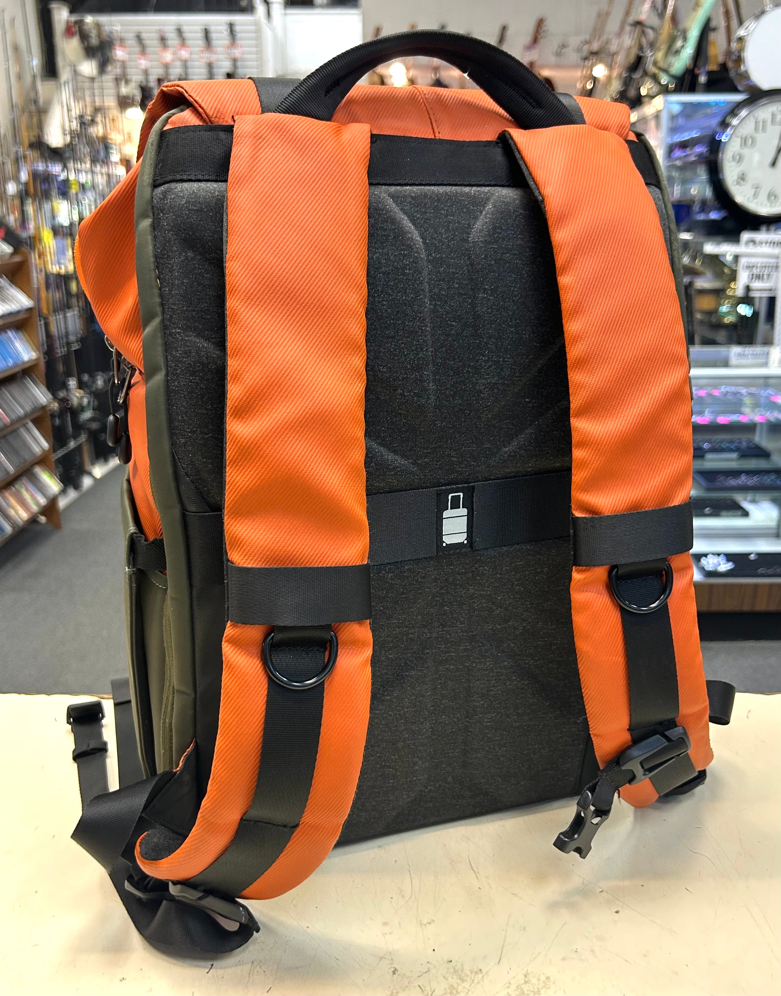 Orange and black padded camera backpack on a counter in a store setting