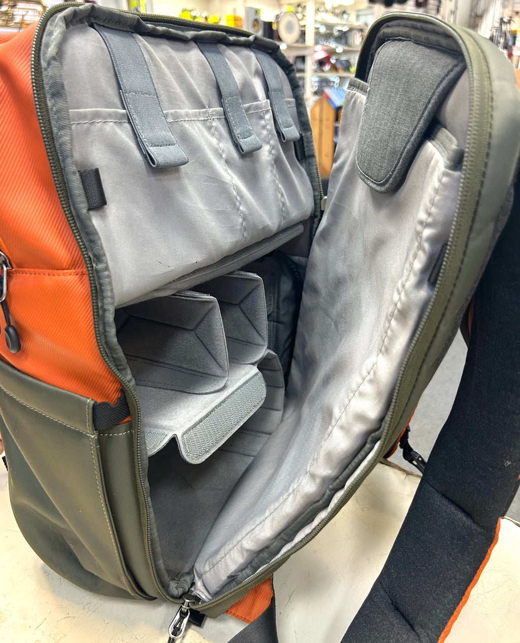 Open camera backpack with gray interior adjustable compartments in a store setting
