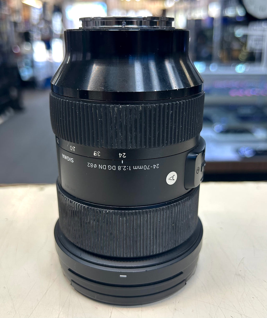 Sigma 24 to 70mm Camera lens on a white surface with a blurred background
