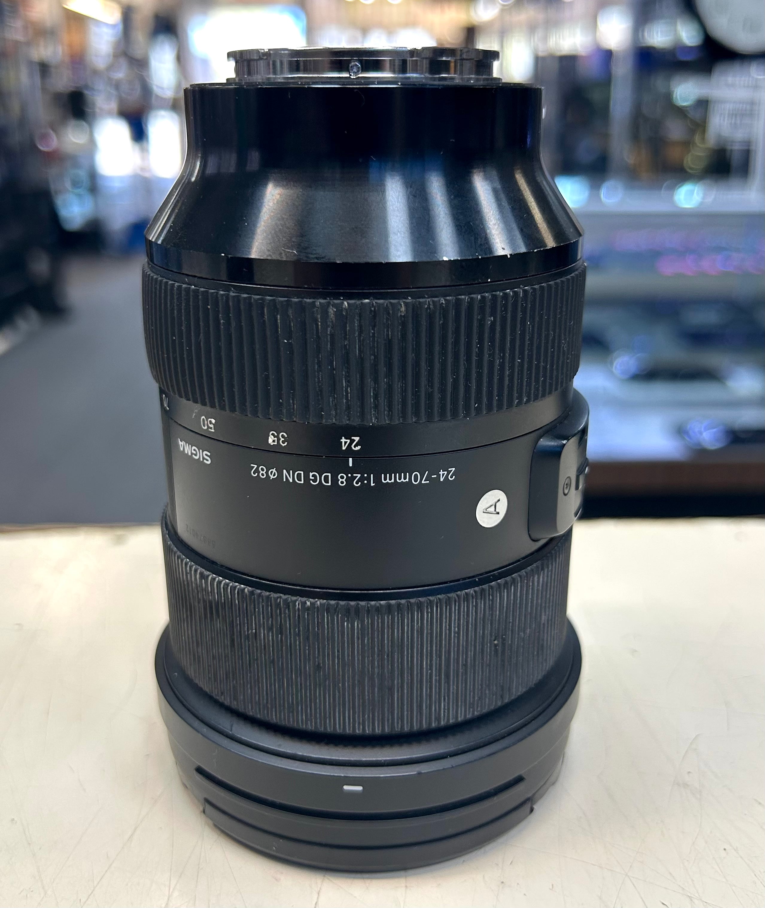 Sigma 24 to 70mm Camera lens on a white surface with a blurred background
