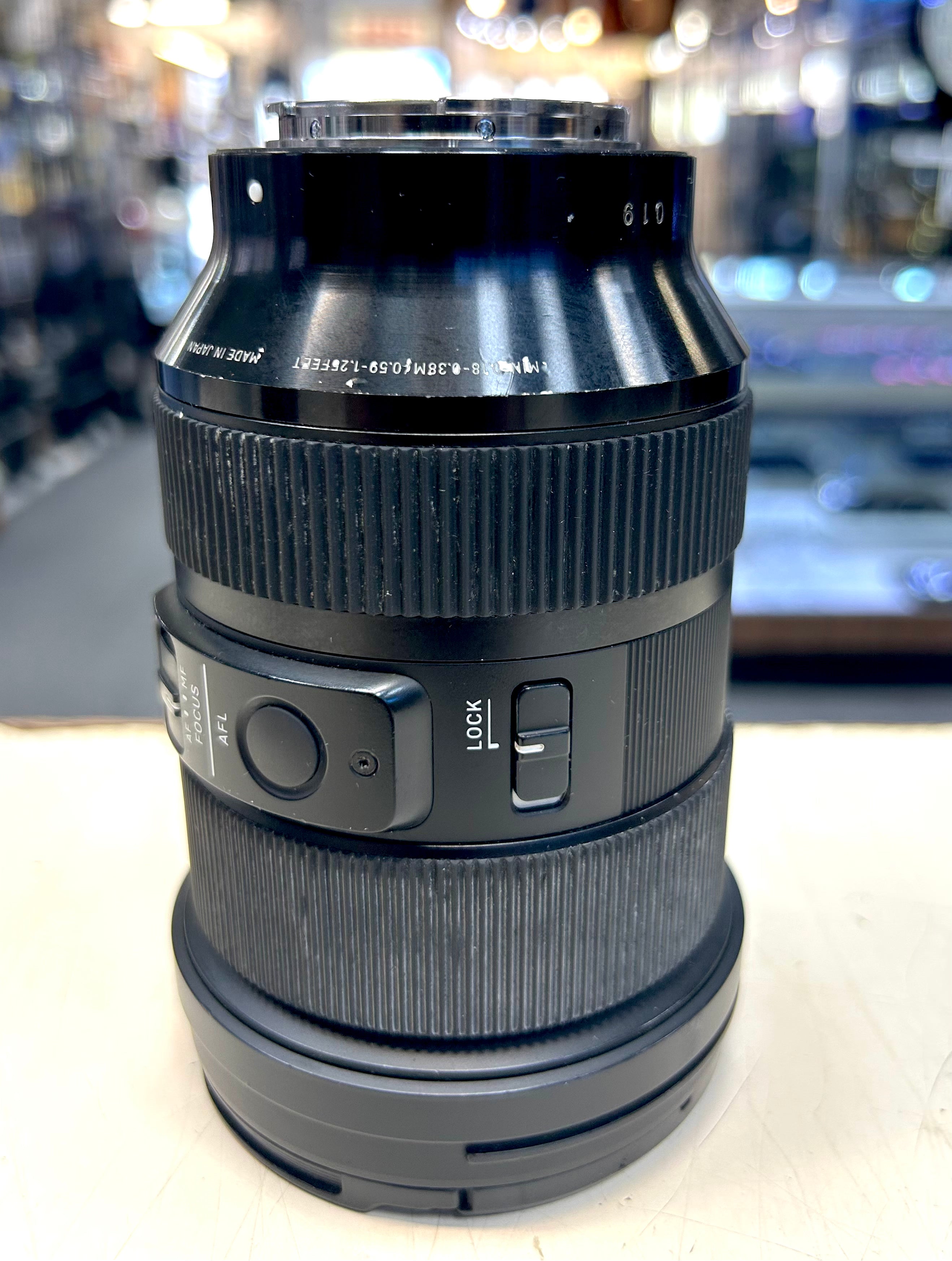 Sigma 70mm Camera lens on a white surface with blurred background