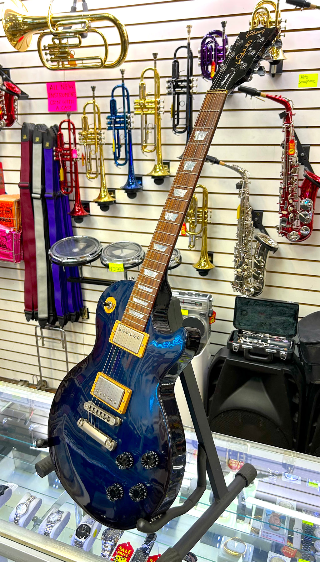 Blue gibson les paul electric guitar on a stand with musical instruments in the background