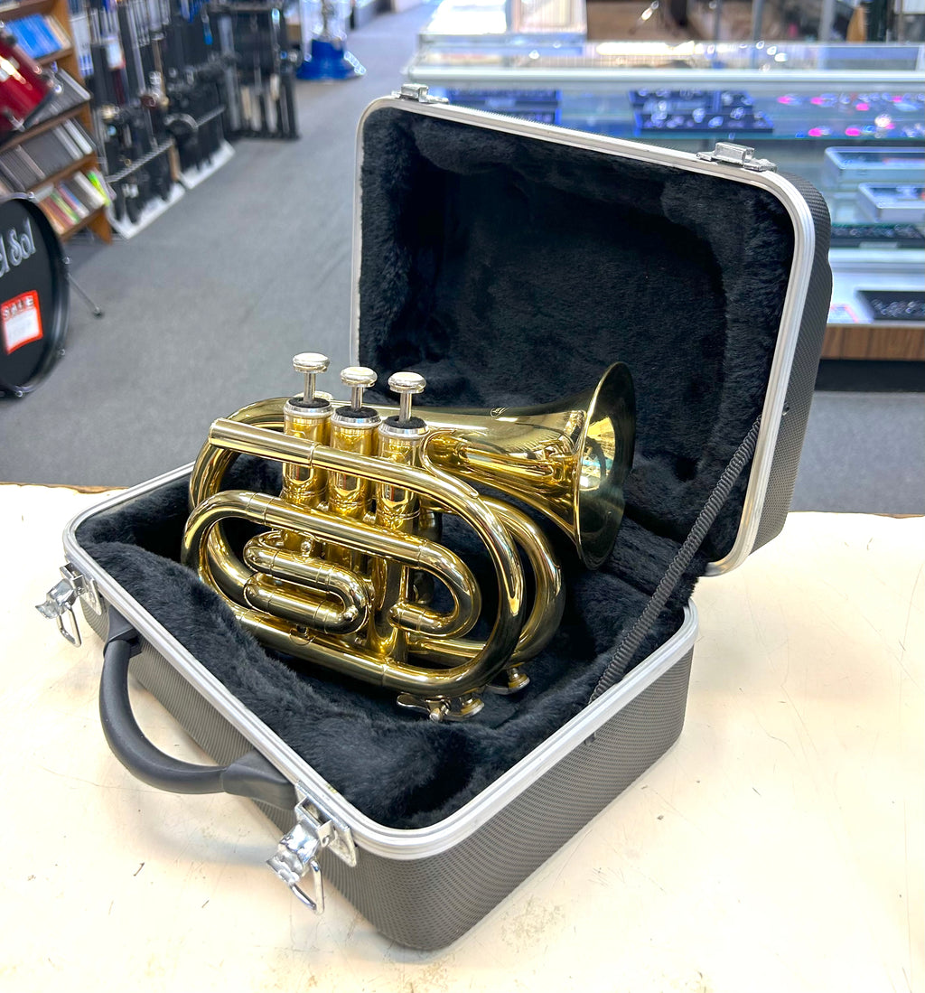 Gold pocket trumpet in a black case on a table with a store background