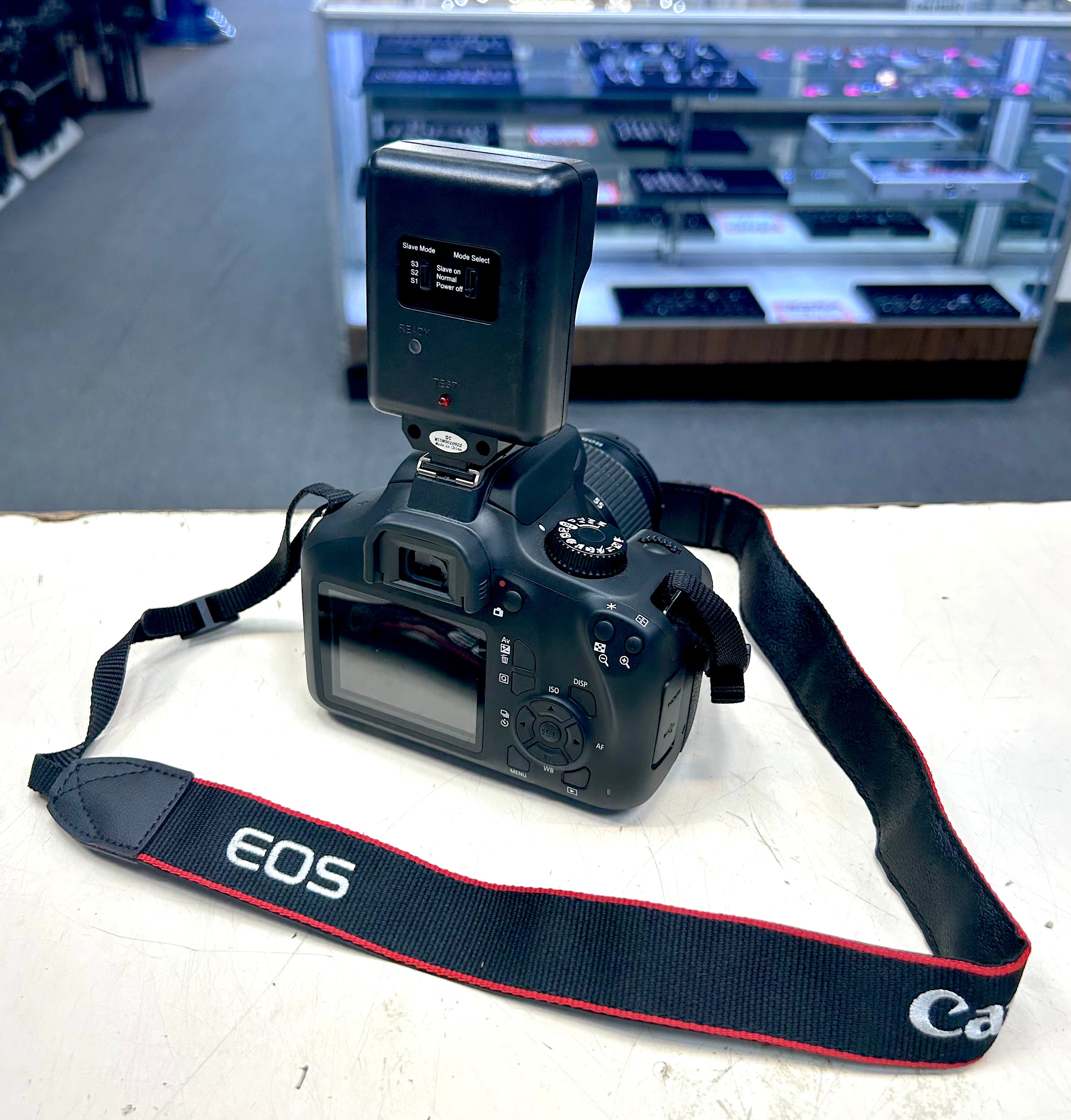 Canon camera with strap on a white surface, blurred store background