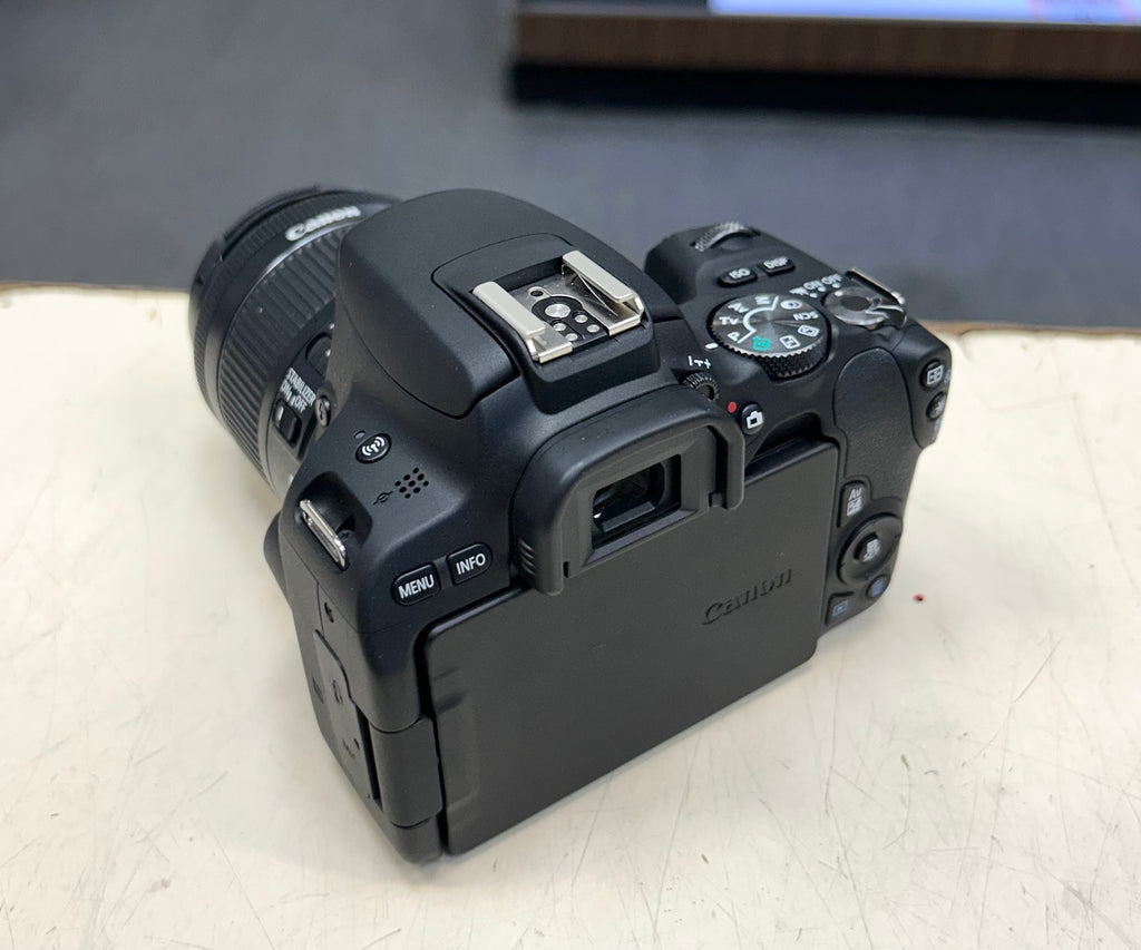 Canon DSLR camera on a white surface with a blurred background