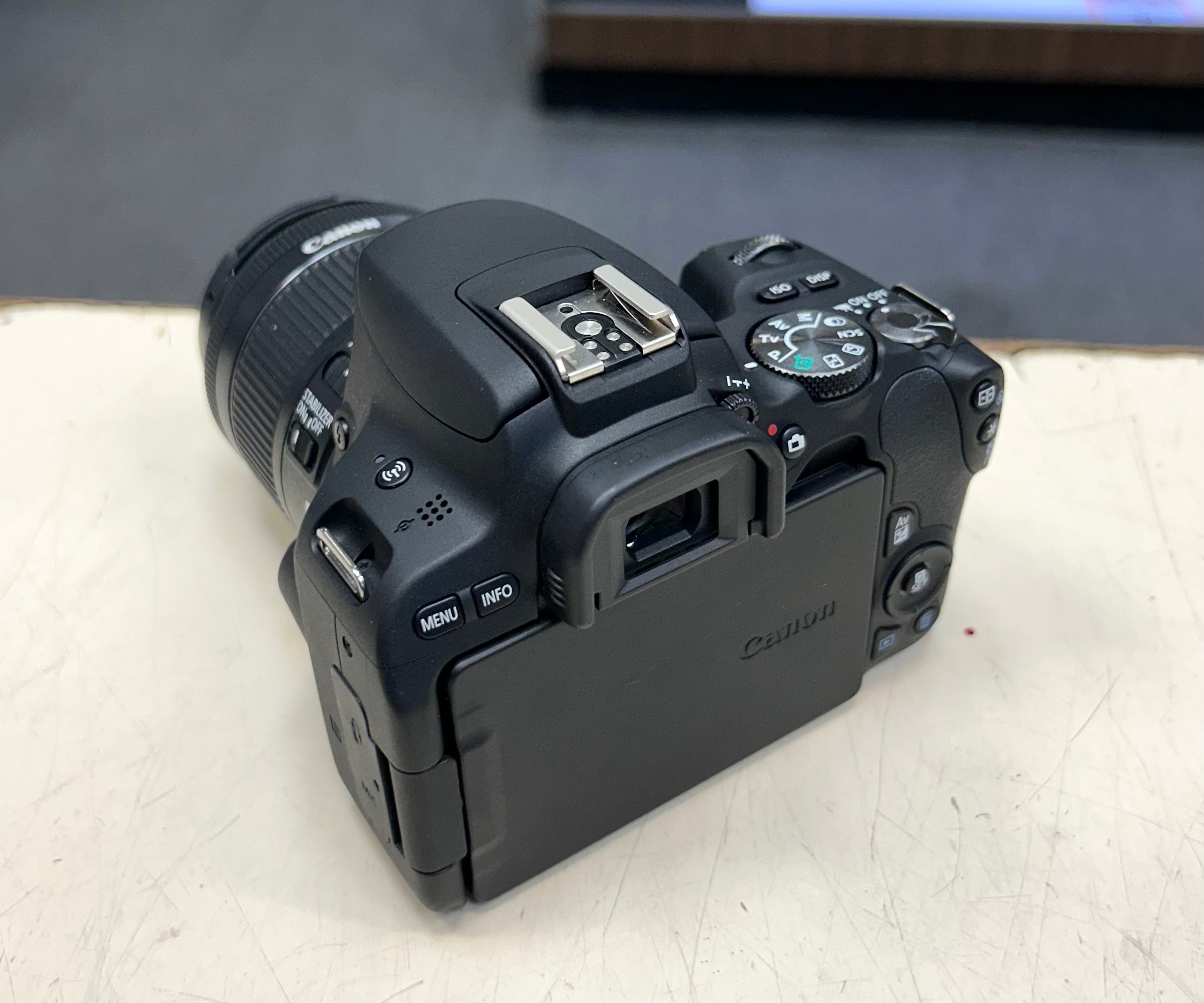 Canon DSLR camera on a white surface with a blurred background