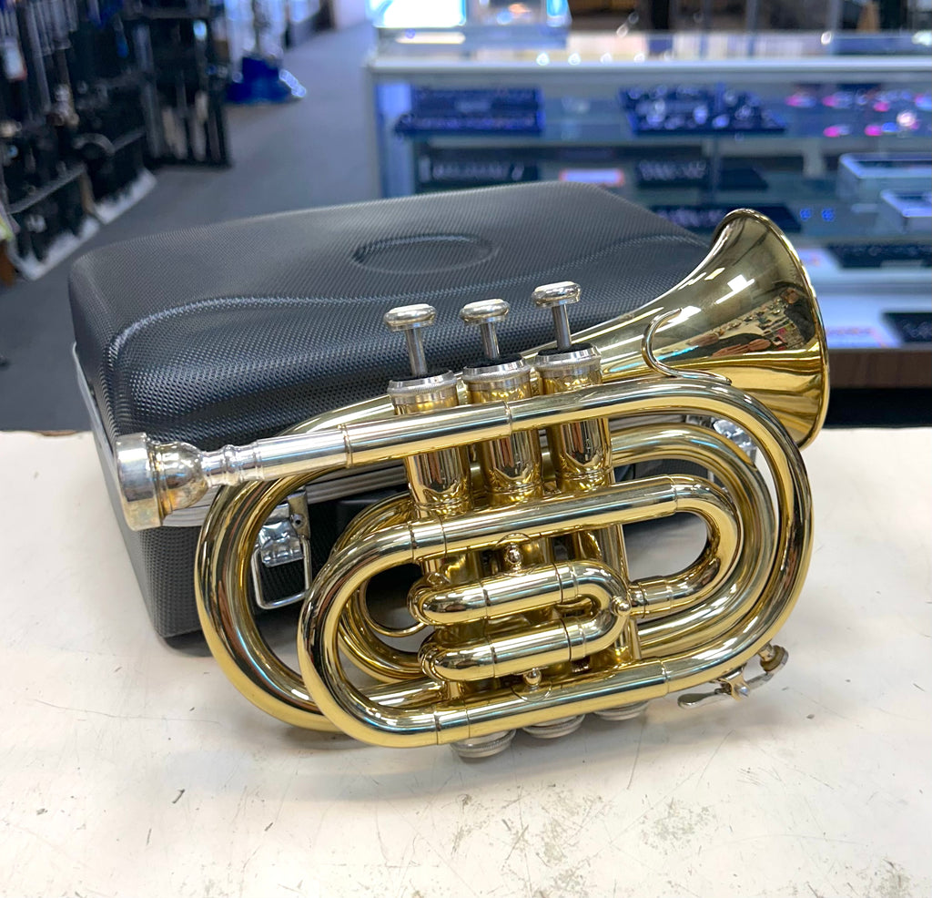 Gold pocket trumpet on a white surface with a blurred background
