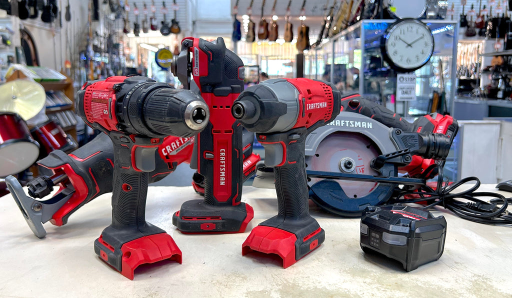 Set of cordless drills and impact driver on a counter with a workshop background