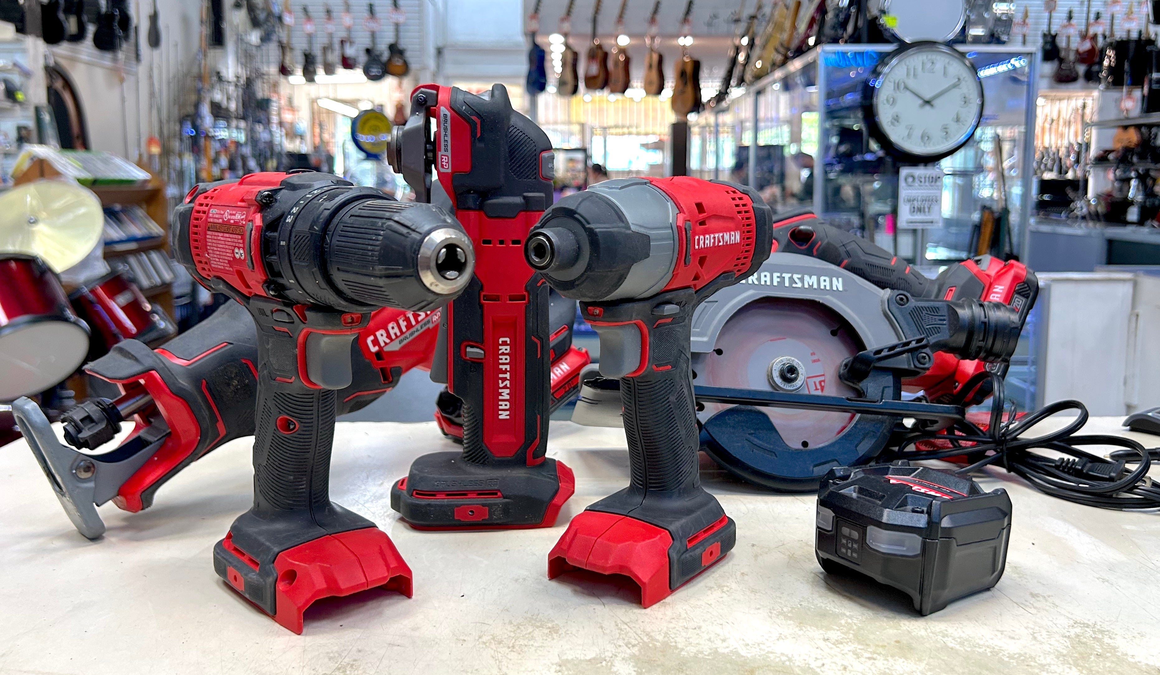 Set of cordless drills and impact driver on a counter with a workshop background