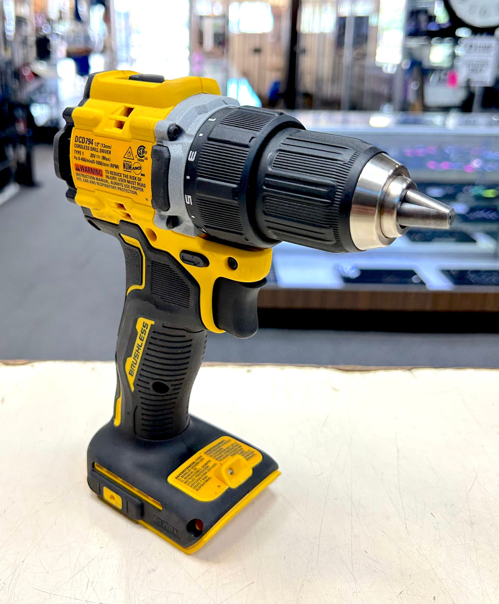 Yellow and black cordless drill on a light surface with a blurred background