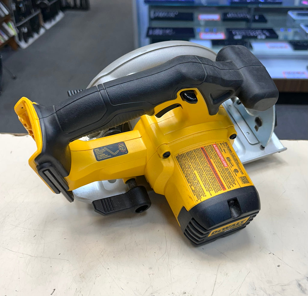 Yellow and black cordless circular saw on a white surface with a blurred background.