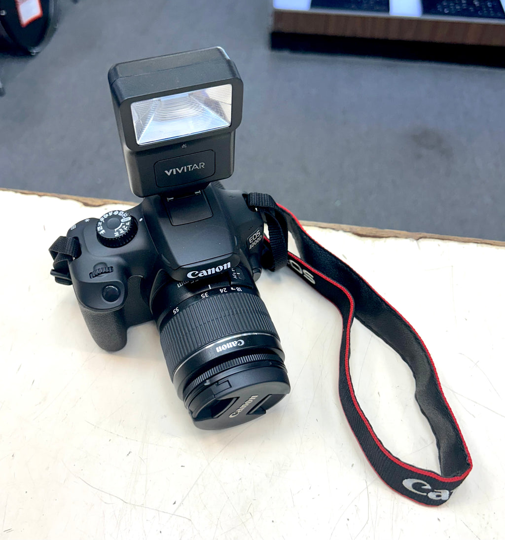 Canon camera with a flash and strap on a light surface
