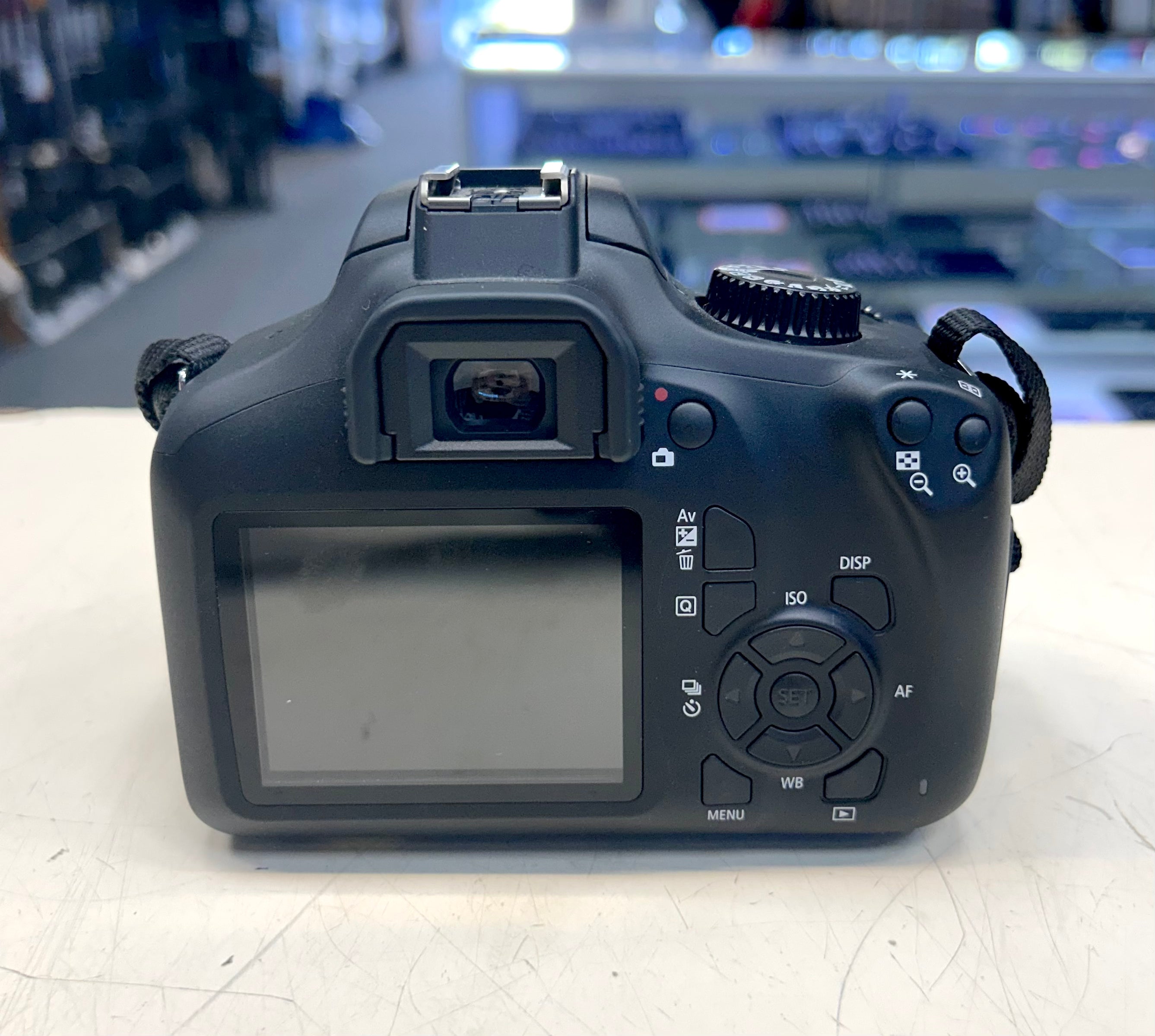Black DSLR camera on a light surface with a blurred indoor background