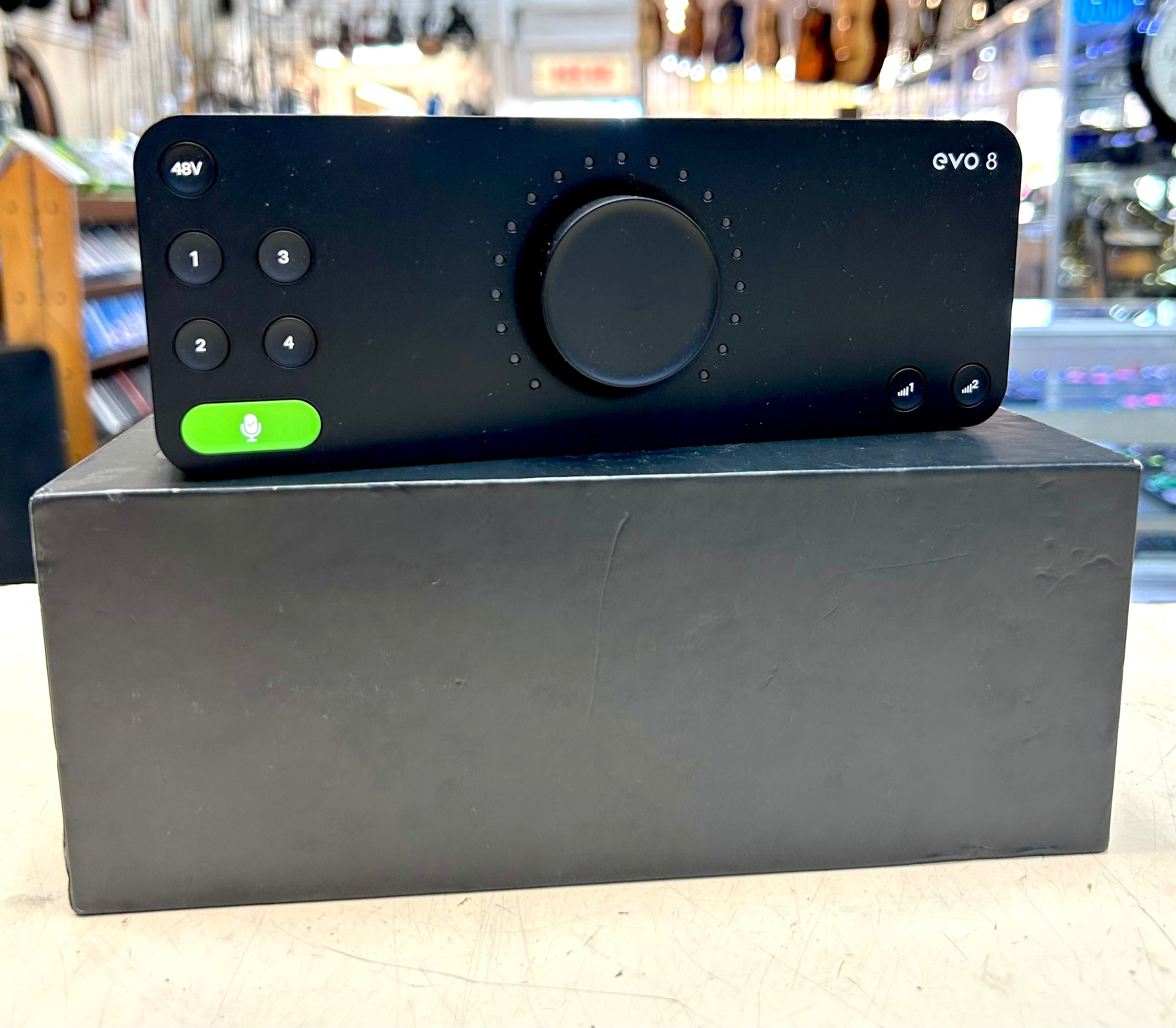 Black audio interface with 'evo 8' branding on a gray stand in a store setting.