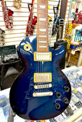 Blue Gibson Les Paul electric guitar with gold hardware on display in a store