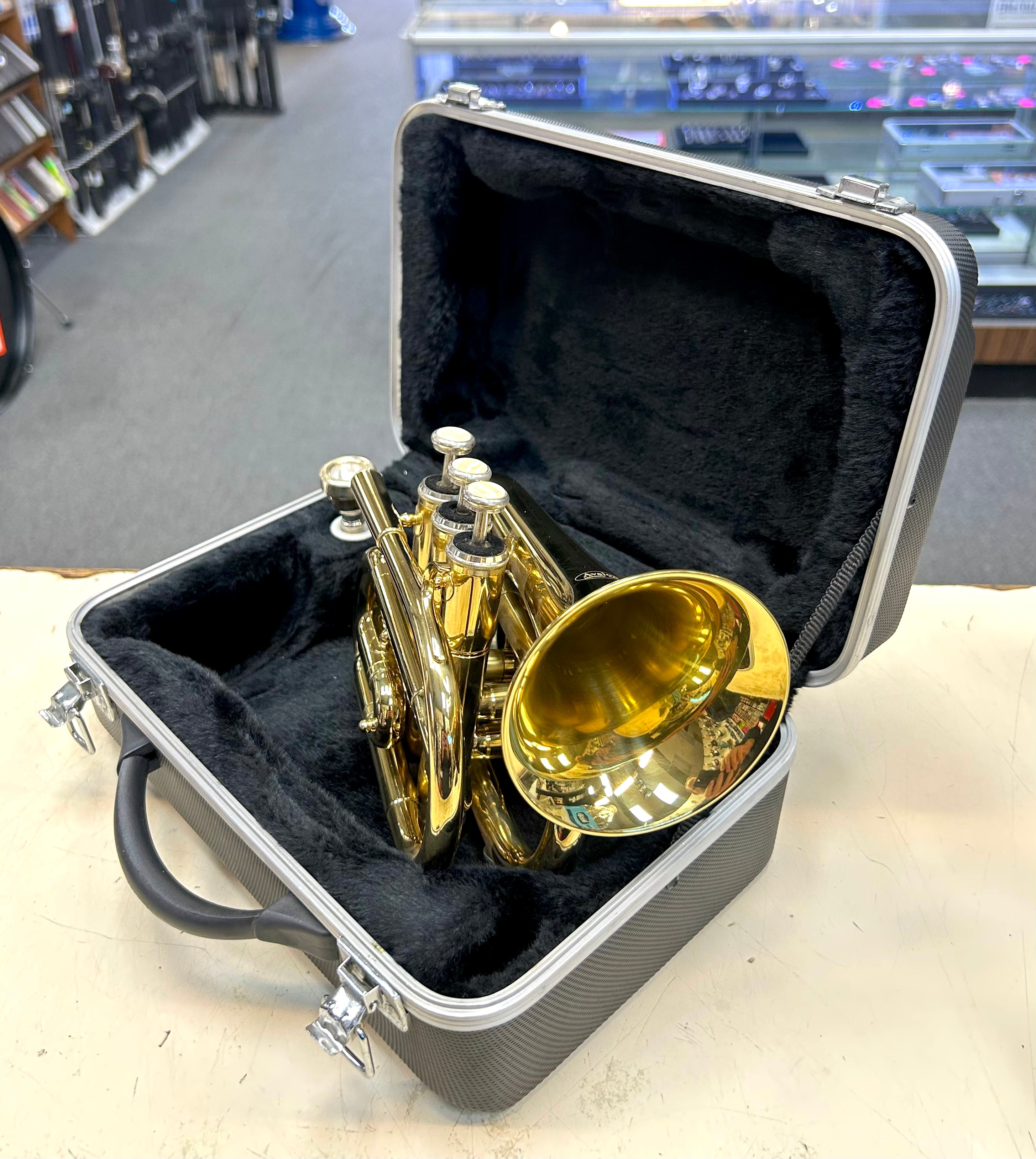 Gold trumpet in a black case on a light surface with a blurred background