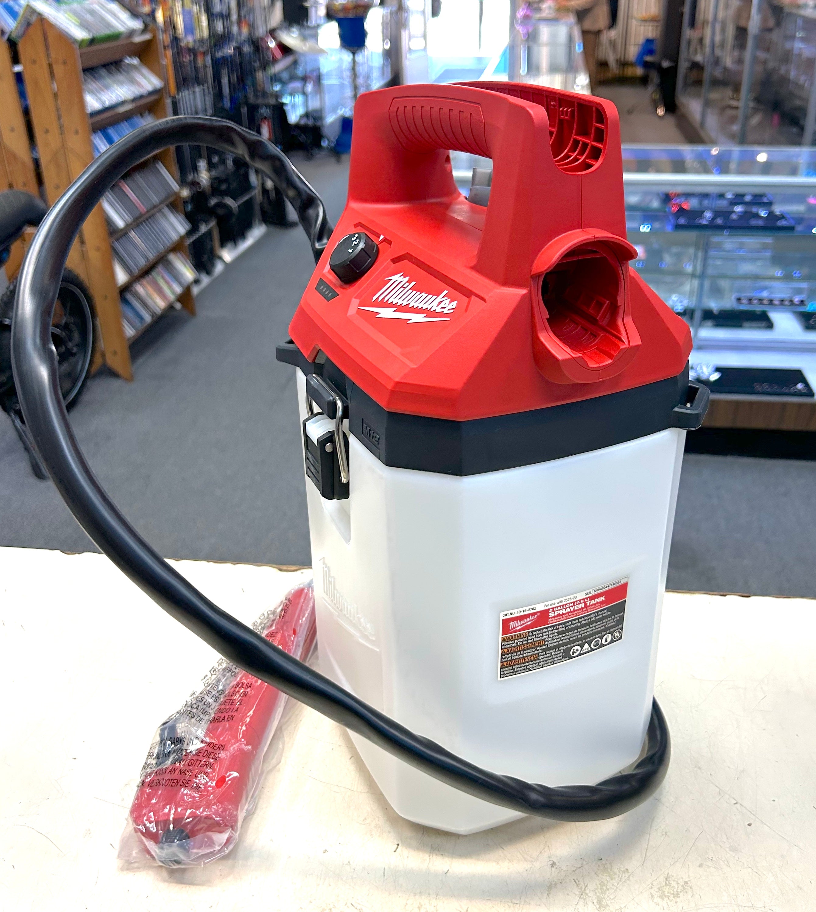 Red and white Milwaukee power washer on a counter in a store setting