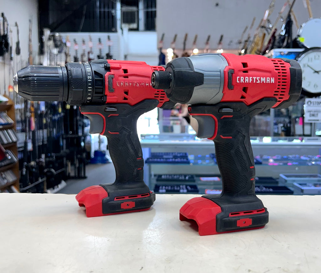 Two Craftsman power tools, a drill and an impact wrench, on a counter with a store background.