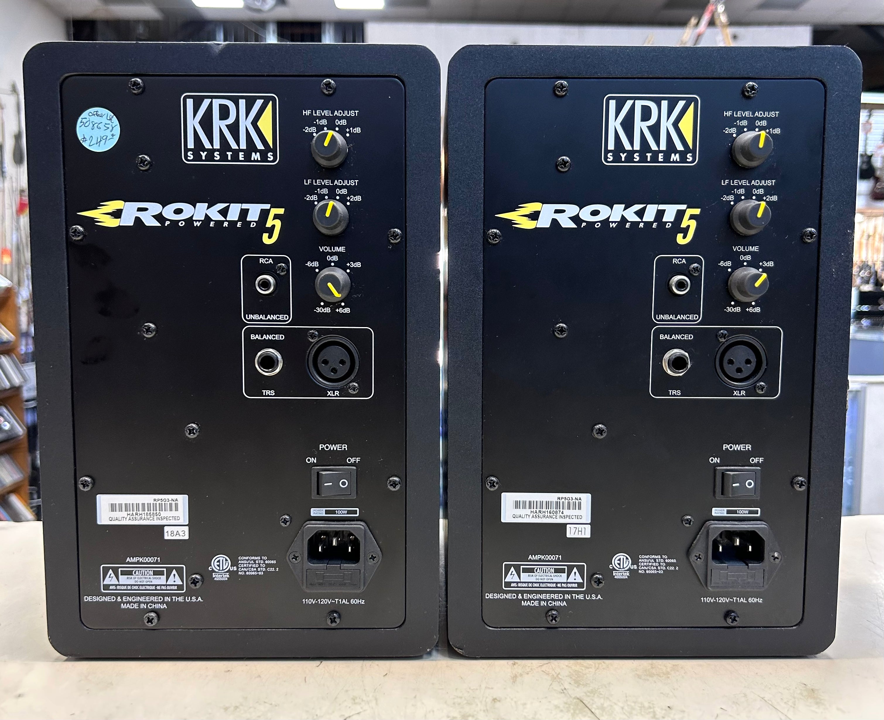 Two KRK Rokit 5 studio monitors showing their back panels with various connectors and labels.