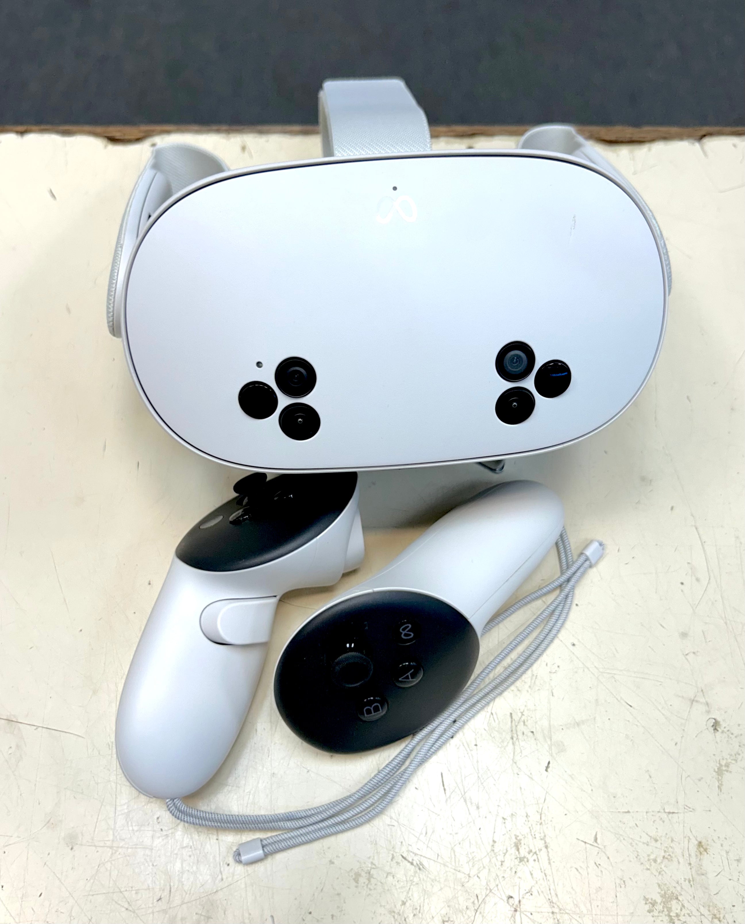Meta Quest 3 White VR headset and controllers on a light surface with a dark background