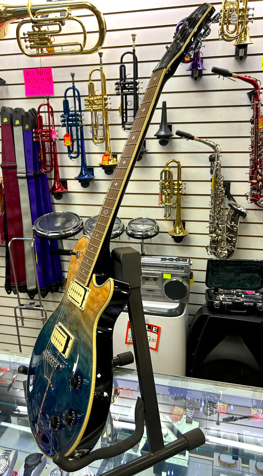 Michael Kelly Electric guitar on a stand with musical instruments in the background