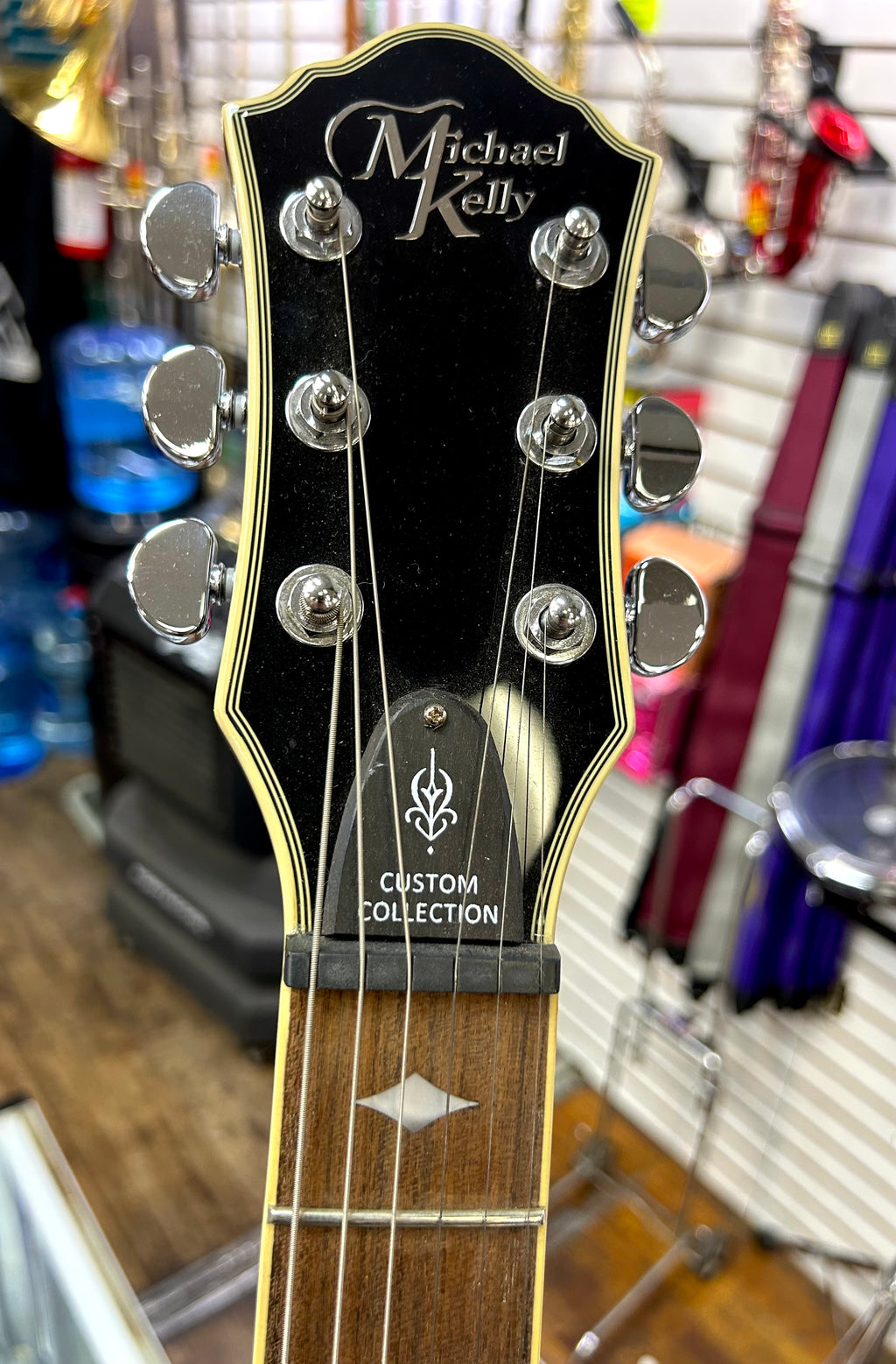 Michael Kelly Guitar headstock with 'Michael Kelly' branding in a store setting
