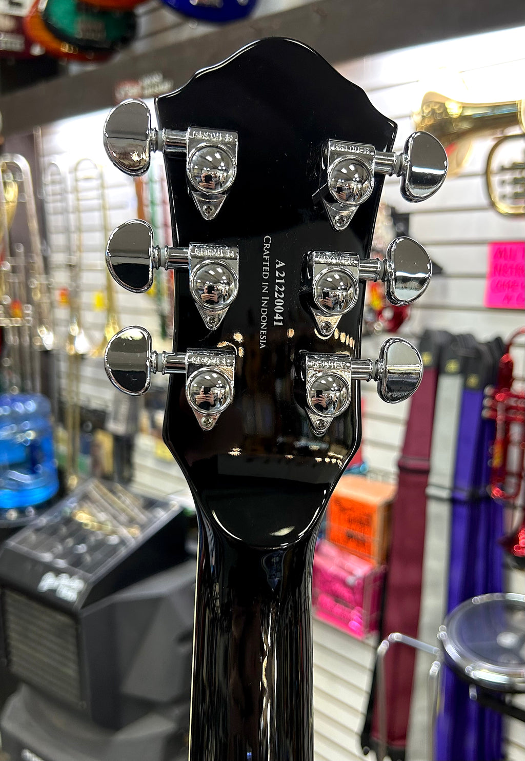 Michael Kelly Guitar headstock with tuning pegs in a music store setting
