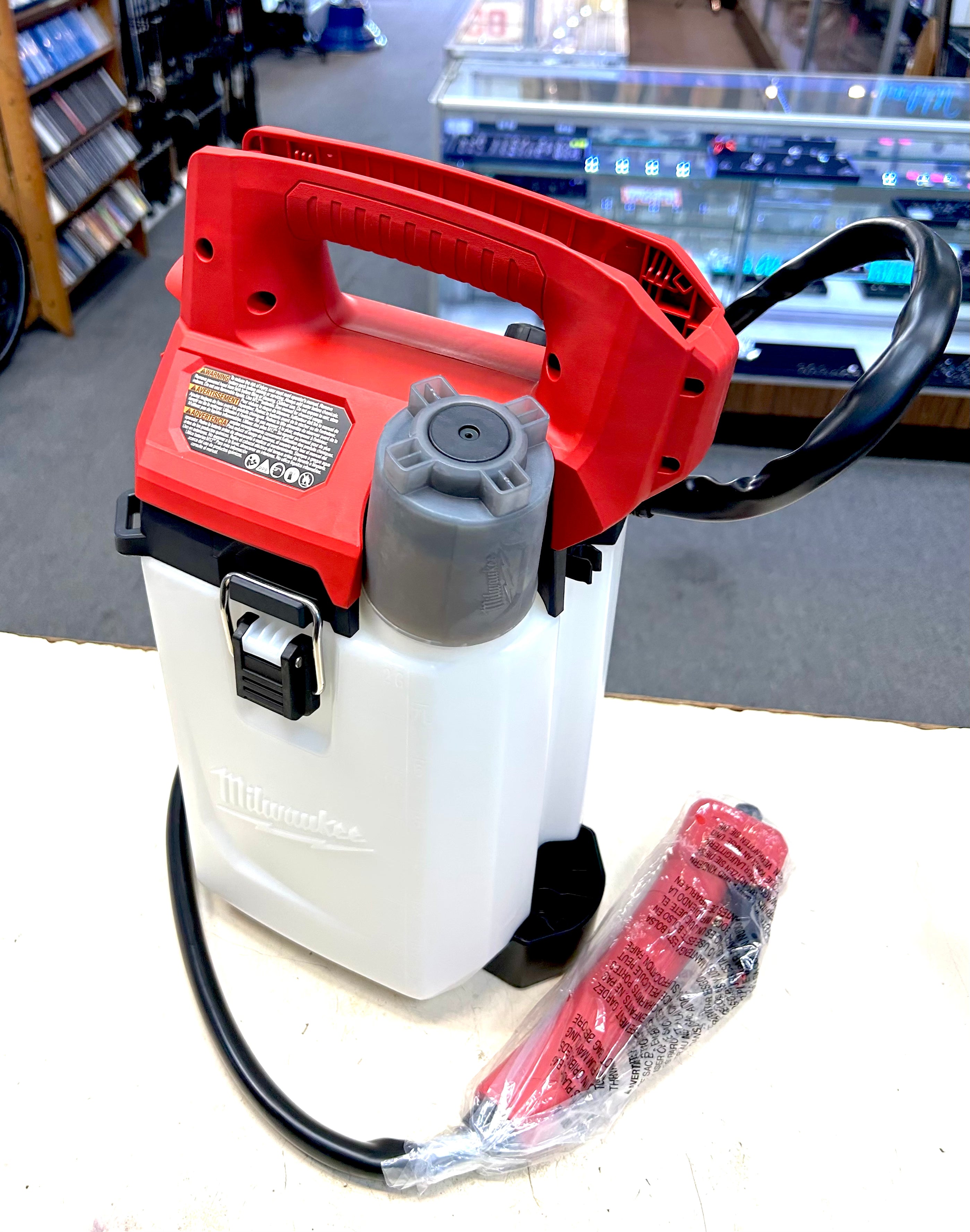 Red and white handheld sprayer with a black hose on a white surface.