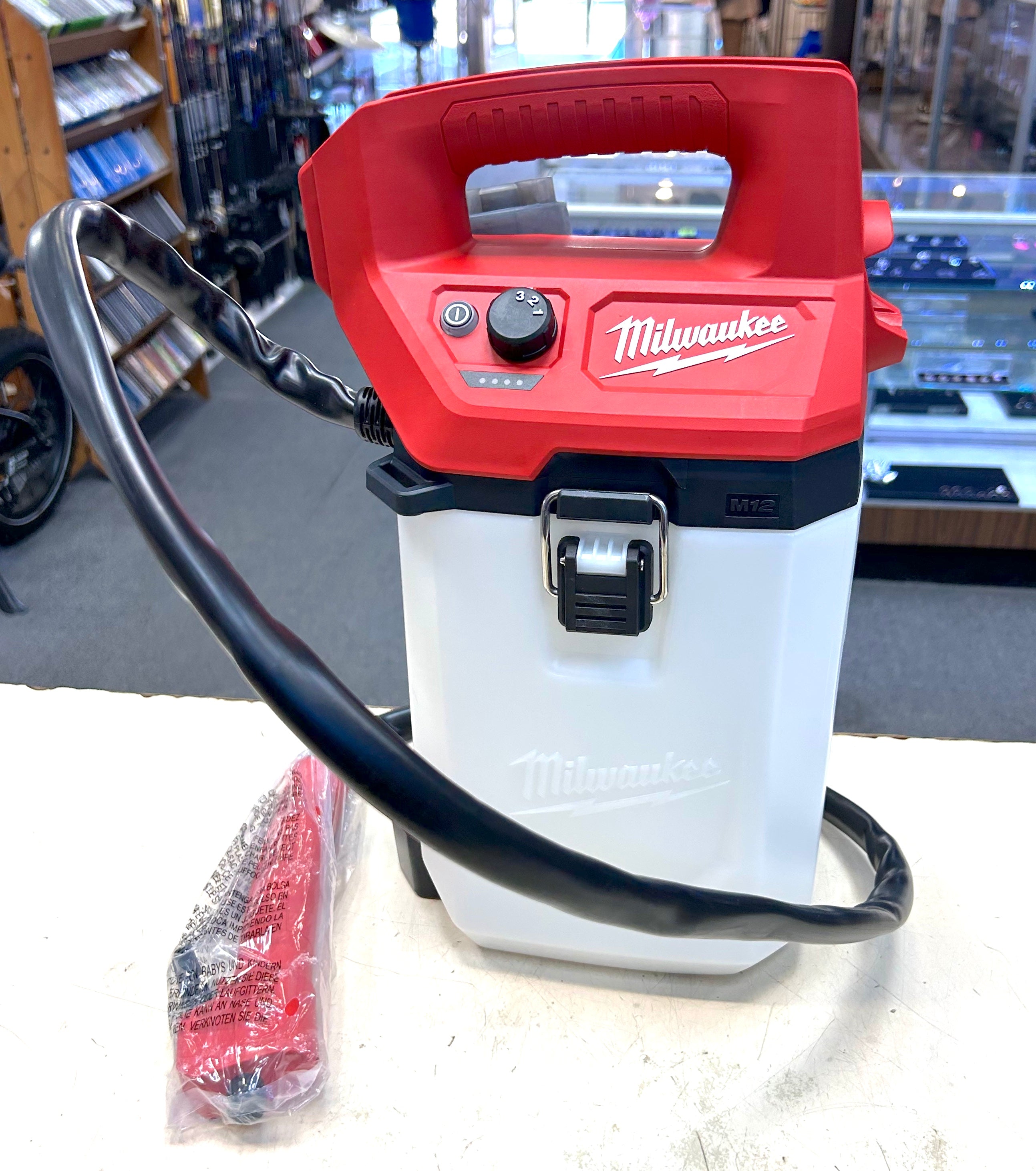 Red and white Milwaukee power tool on a white surface with a blurred background