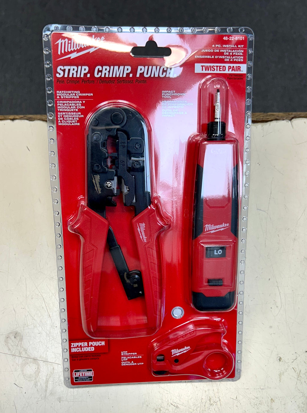 Milwaukee strip, crimp, and punch tool set in packaging on a gray background