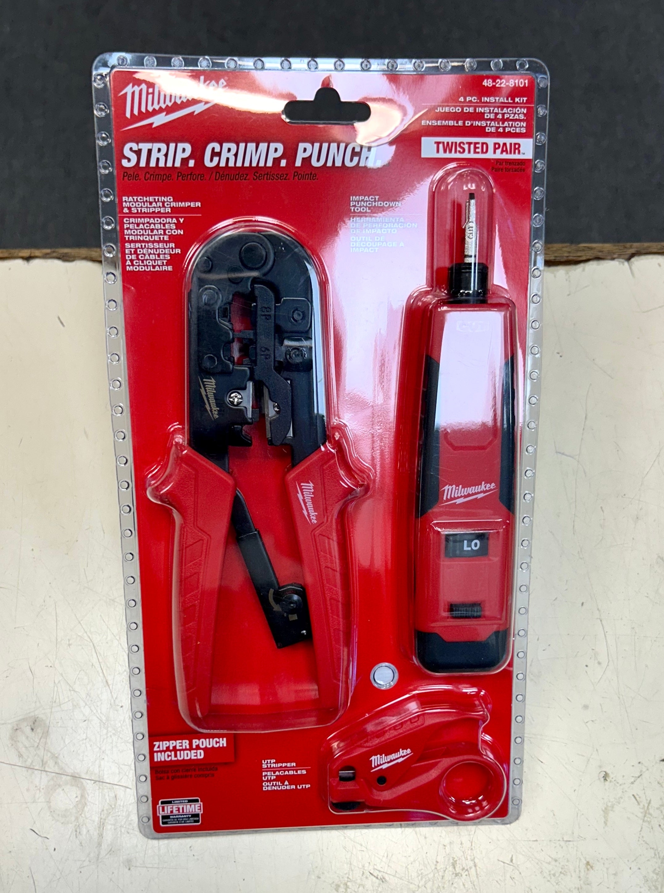 Milwaukee strip, crimp, and punch tool set in packaging on a gray background