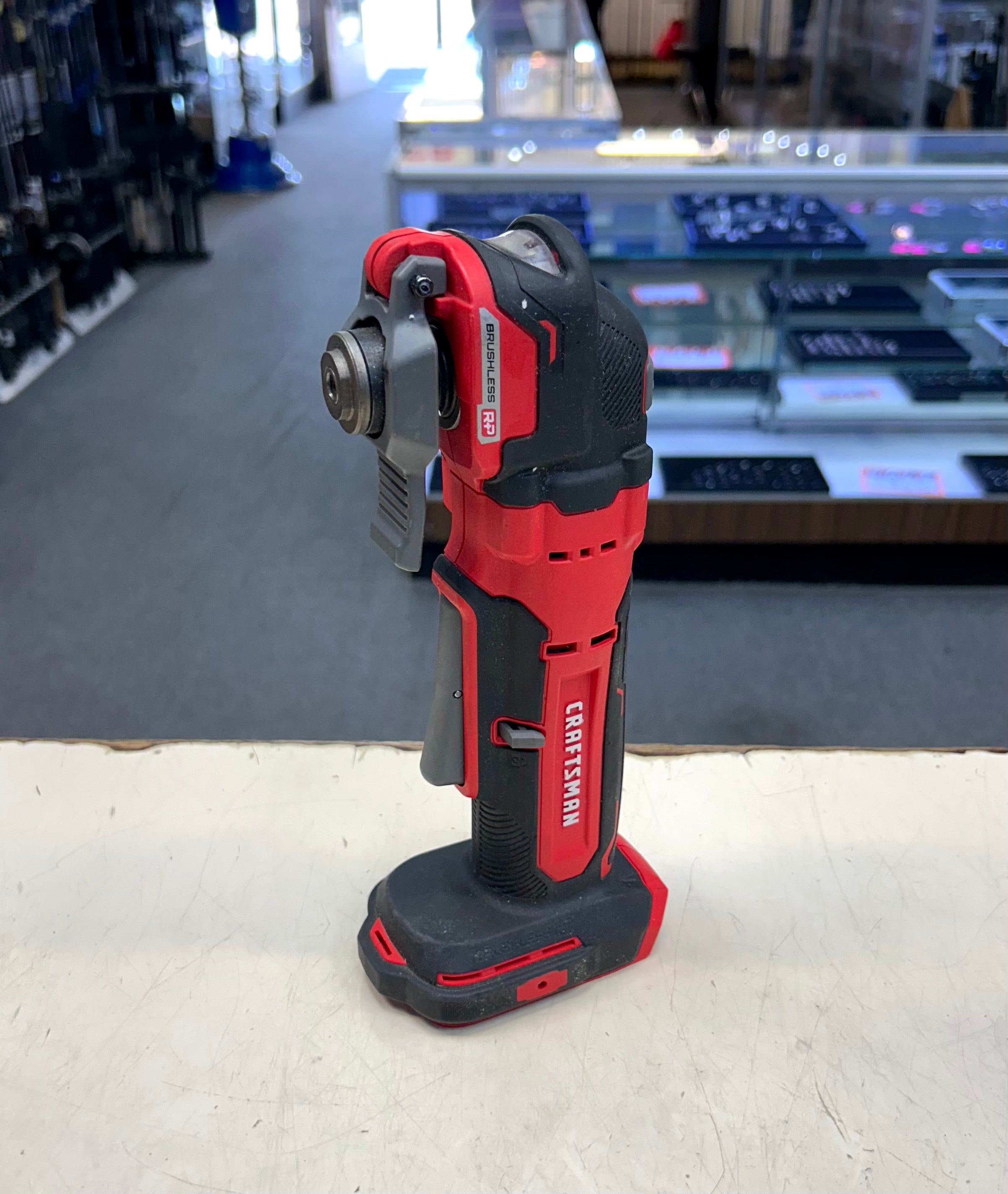 Red and black power tool on a counter with a store setting in the background