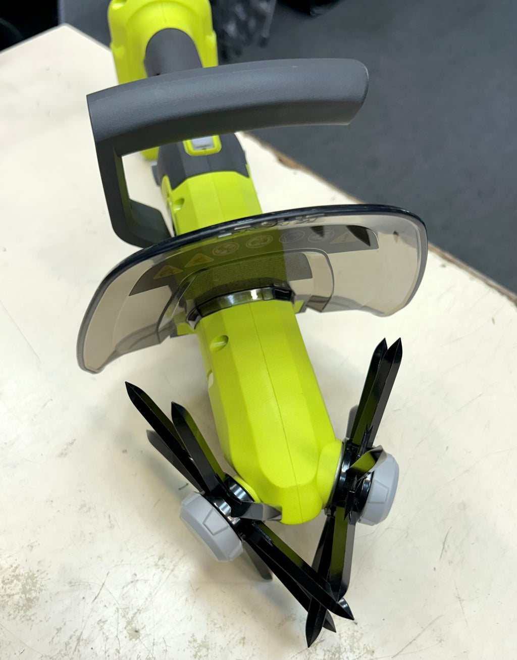 Close-up of a green and black power tool on a white surface