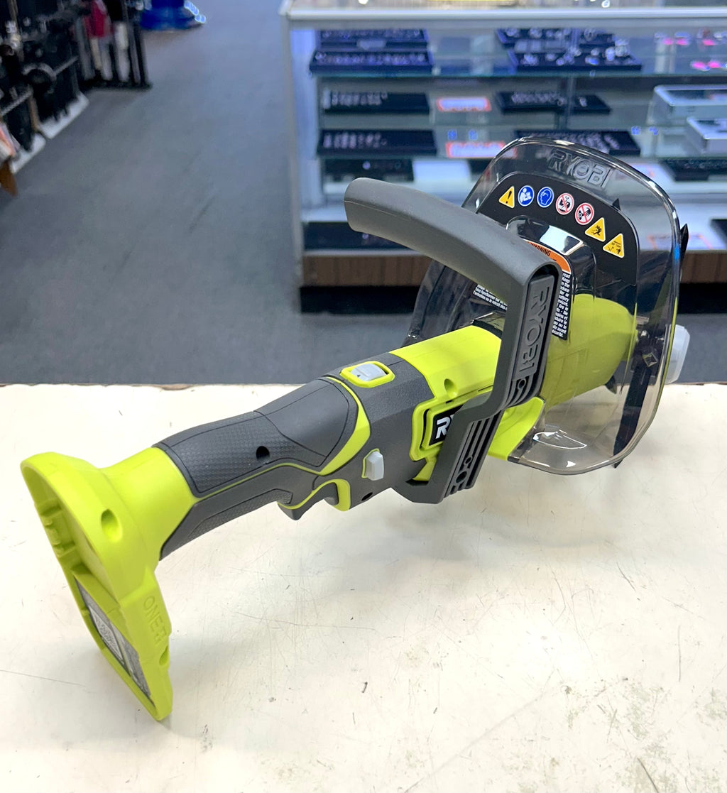Green and gray power tool on a white surface with a blurred store background