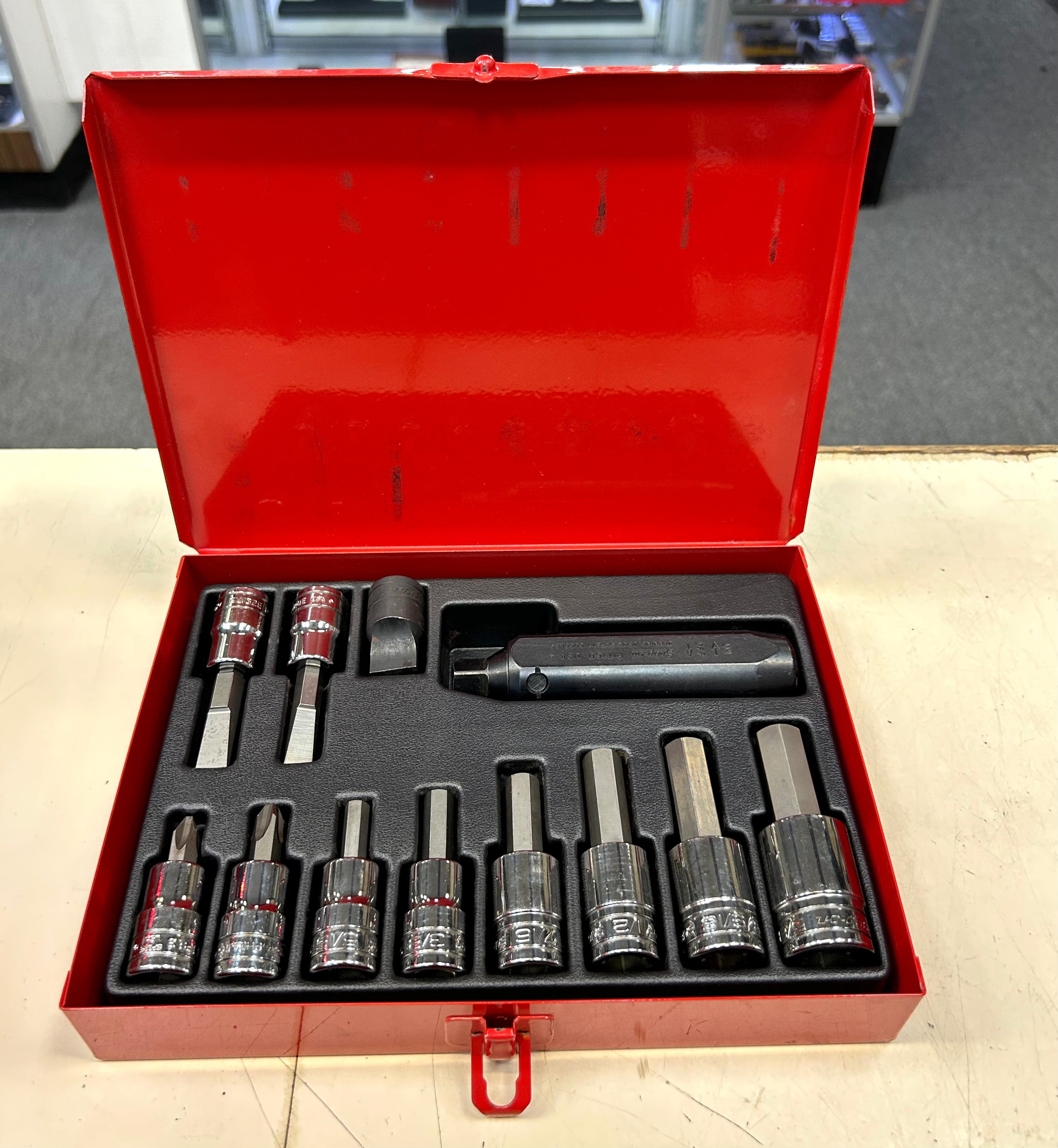 Set of socket tools in a red toolbox on a tiled floor.