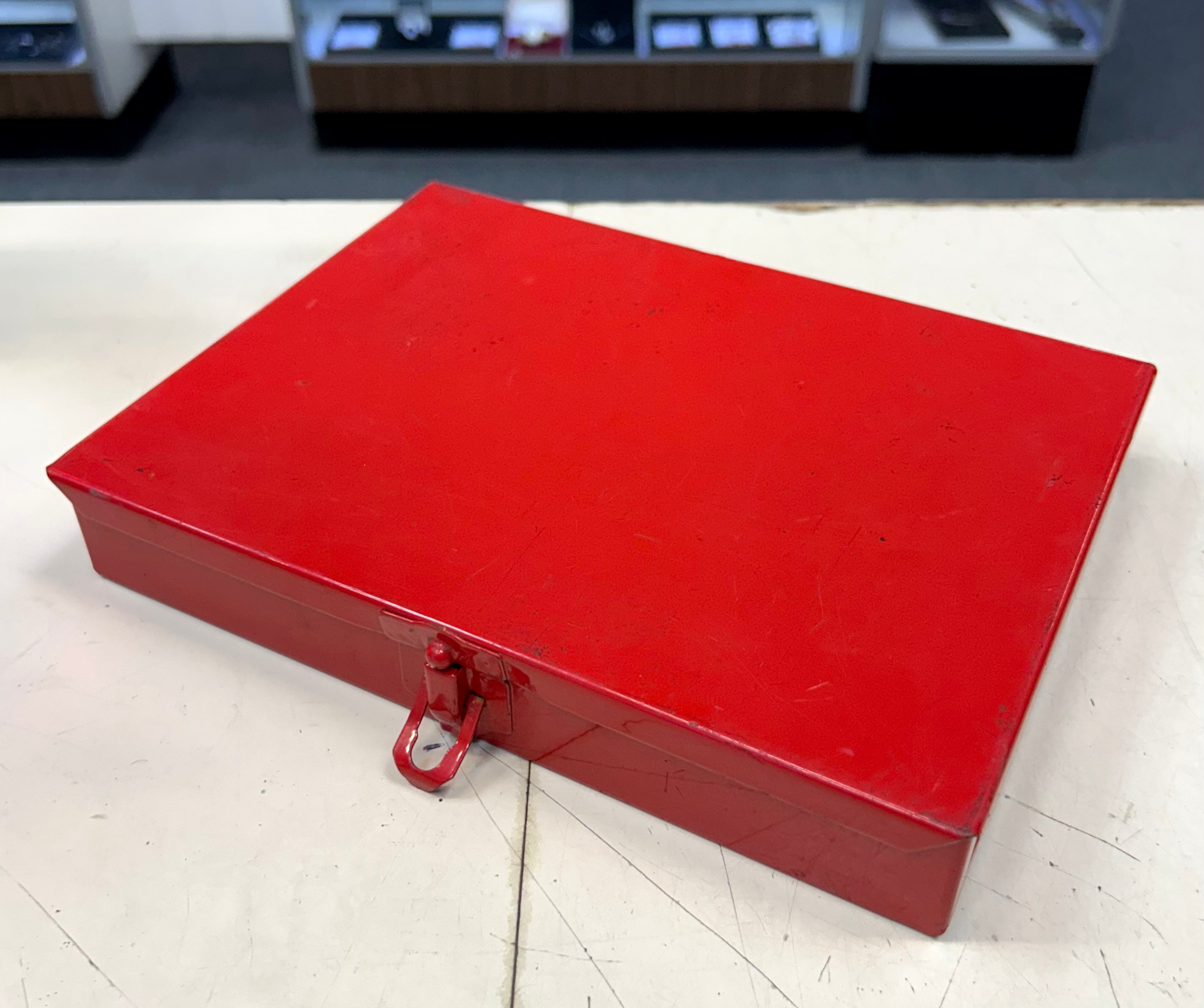Red metal toolbox on a white surface with a blurred background