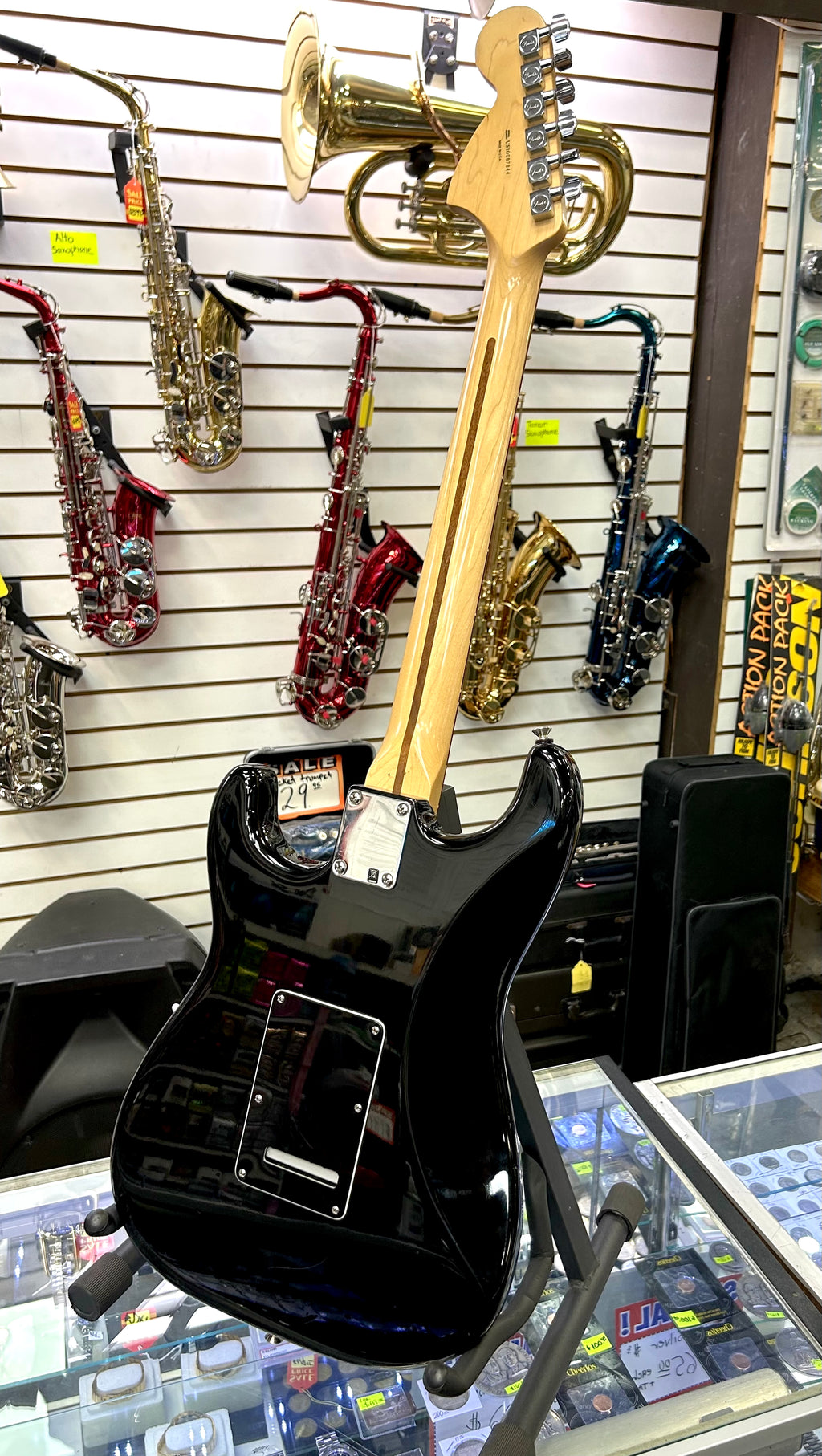 Black electric fender guitar with gold hardware on display in a music store.
