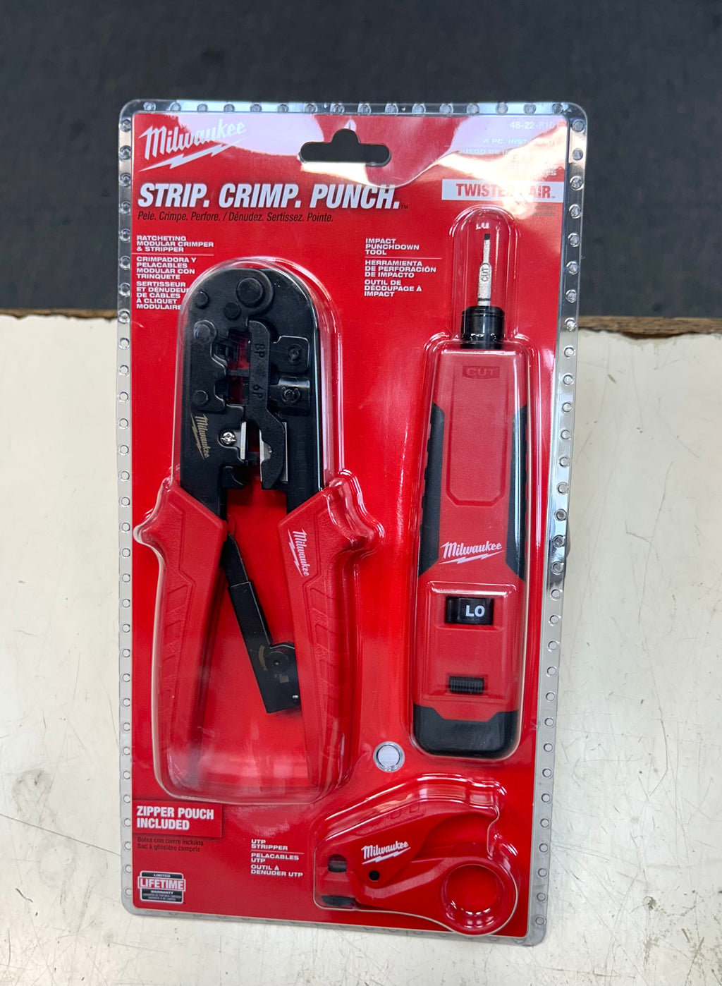 Milwaukee strip, crimp, punch tool set in packaging on a textured surface