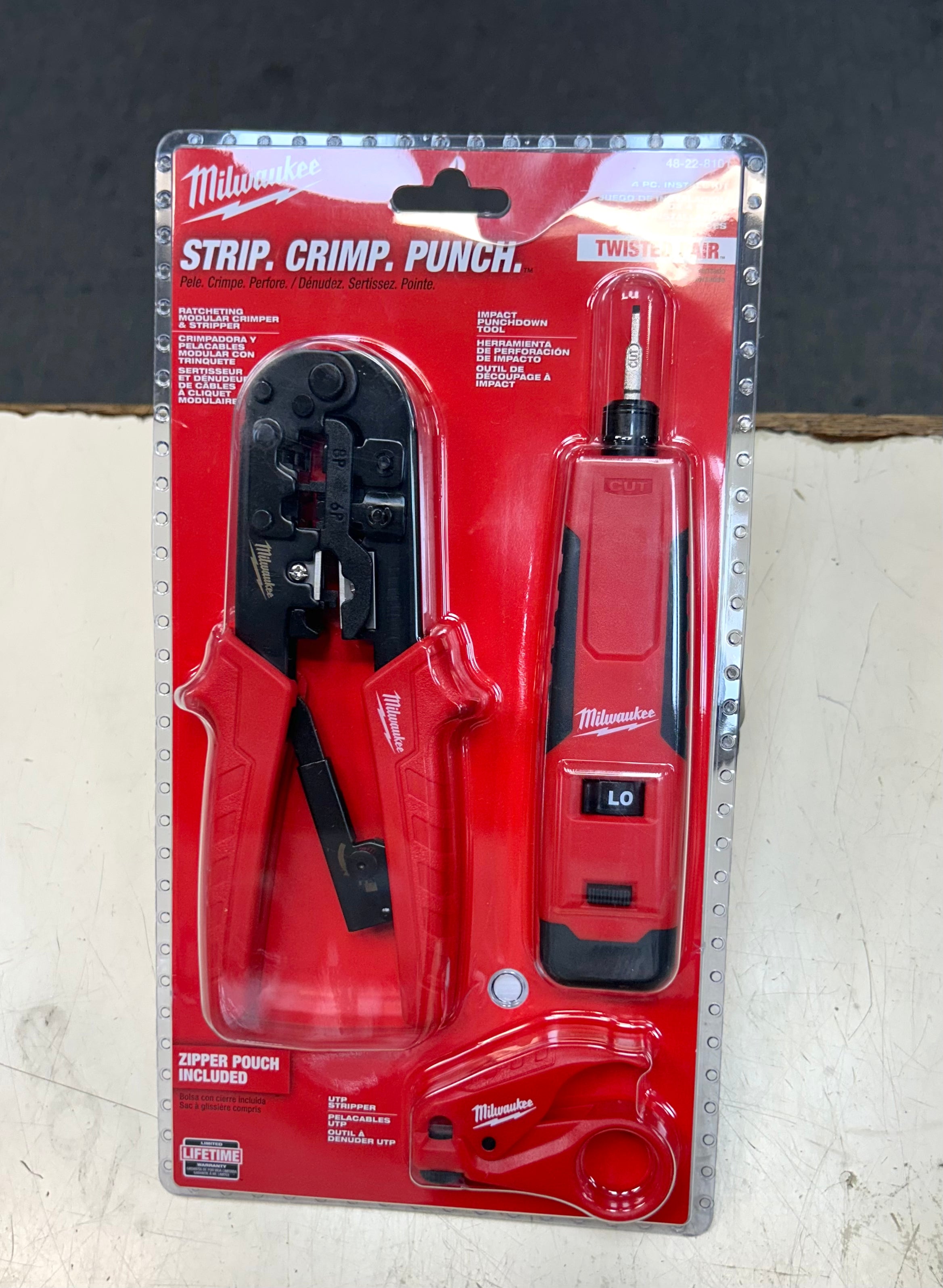 Milwaukee strip, crimp, punch tool set in packaging on a textured surface